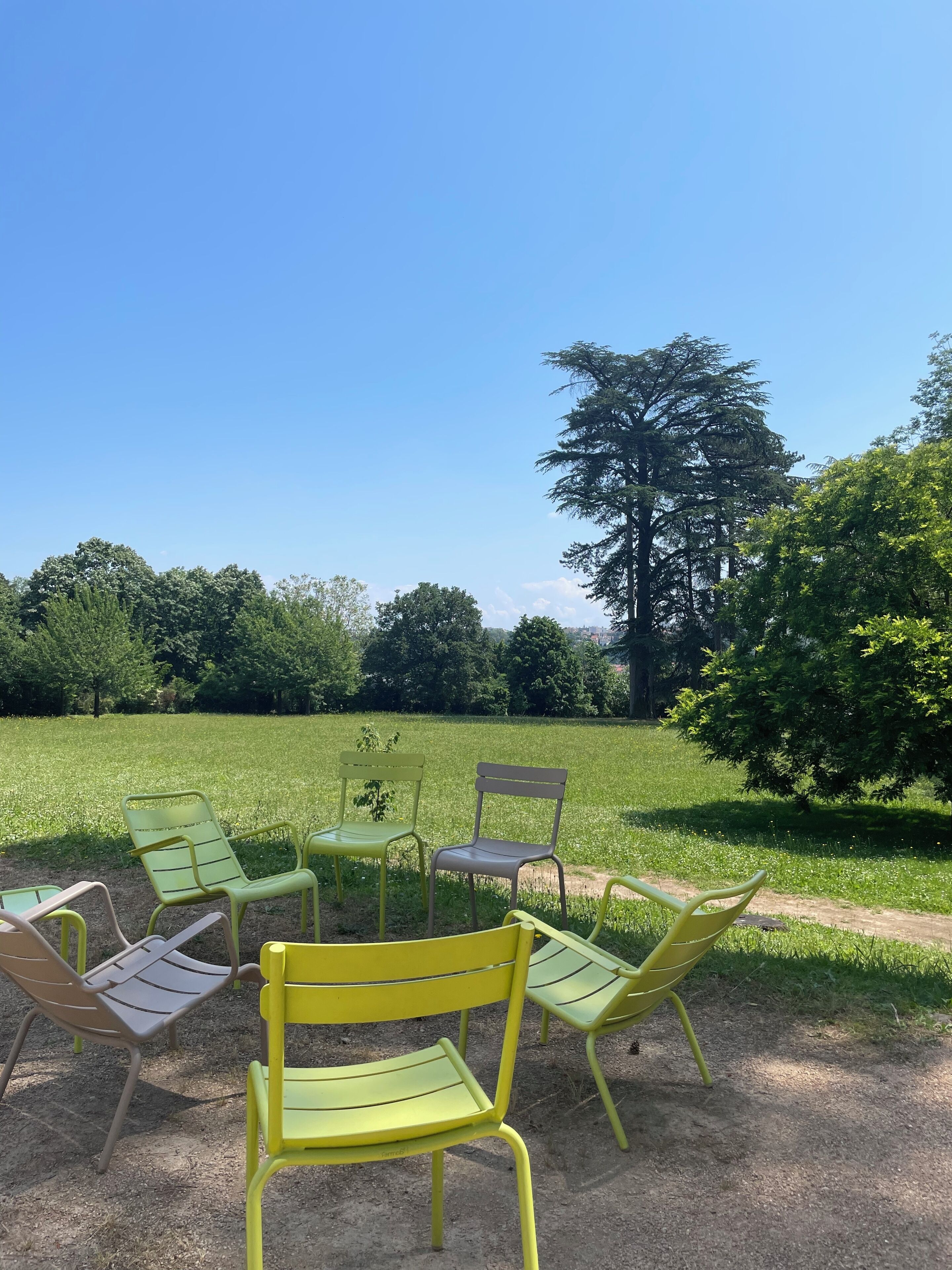 Outdoor seating with a view of a grassy field and trees.