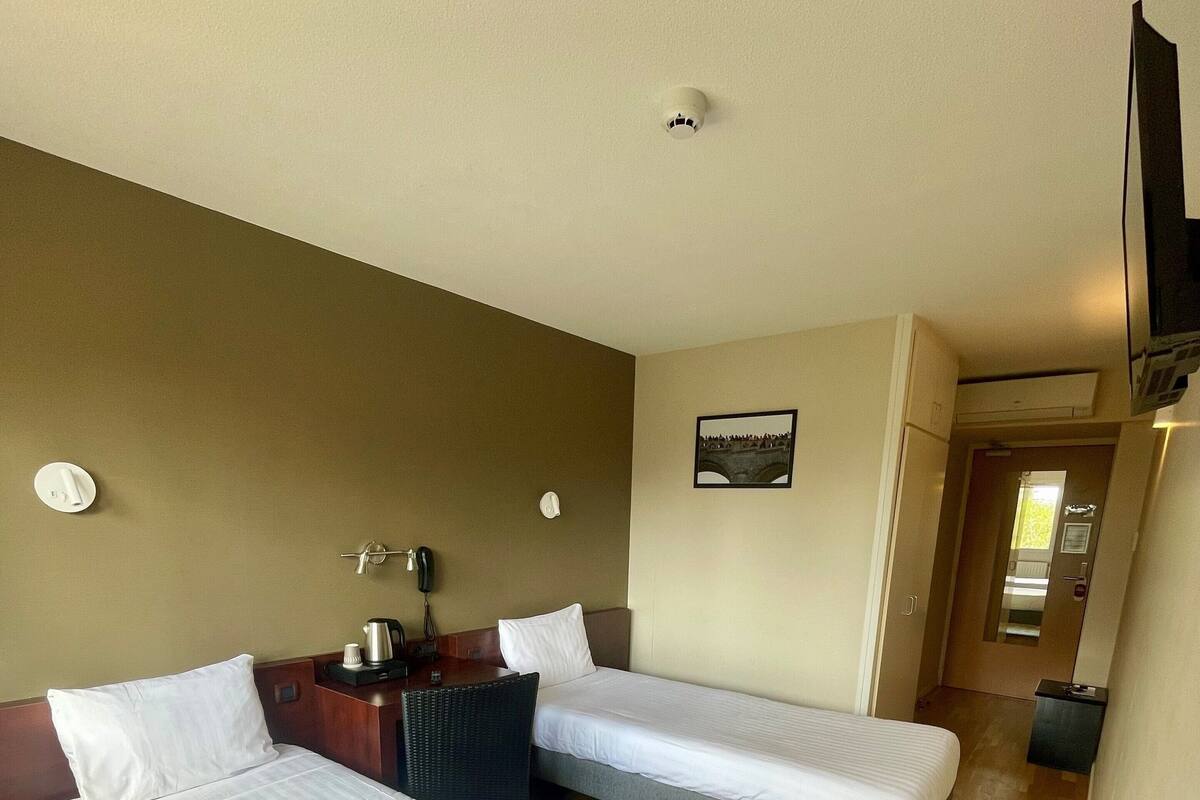 A hotel room with two beds, a desk with a chair, a telephone, and a picture on the wall.