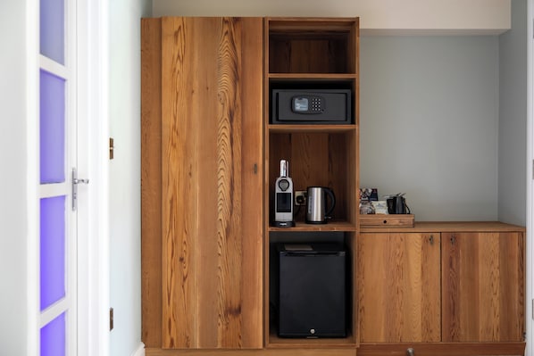 Una cocina compacta con armarios de madera, microondas, cafetera y refrigerador pequeño.