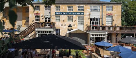 Un edificio con un letrero que dice "The Head of the River" y mesas al aire libre con sombrillas.