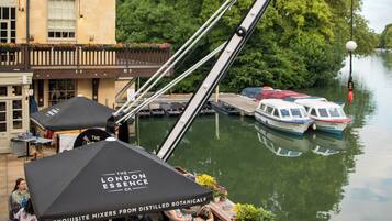 An outdoor seating area with wicker furniture and a table under a canopy advertising 'The London Essence Co.'