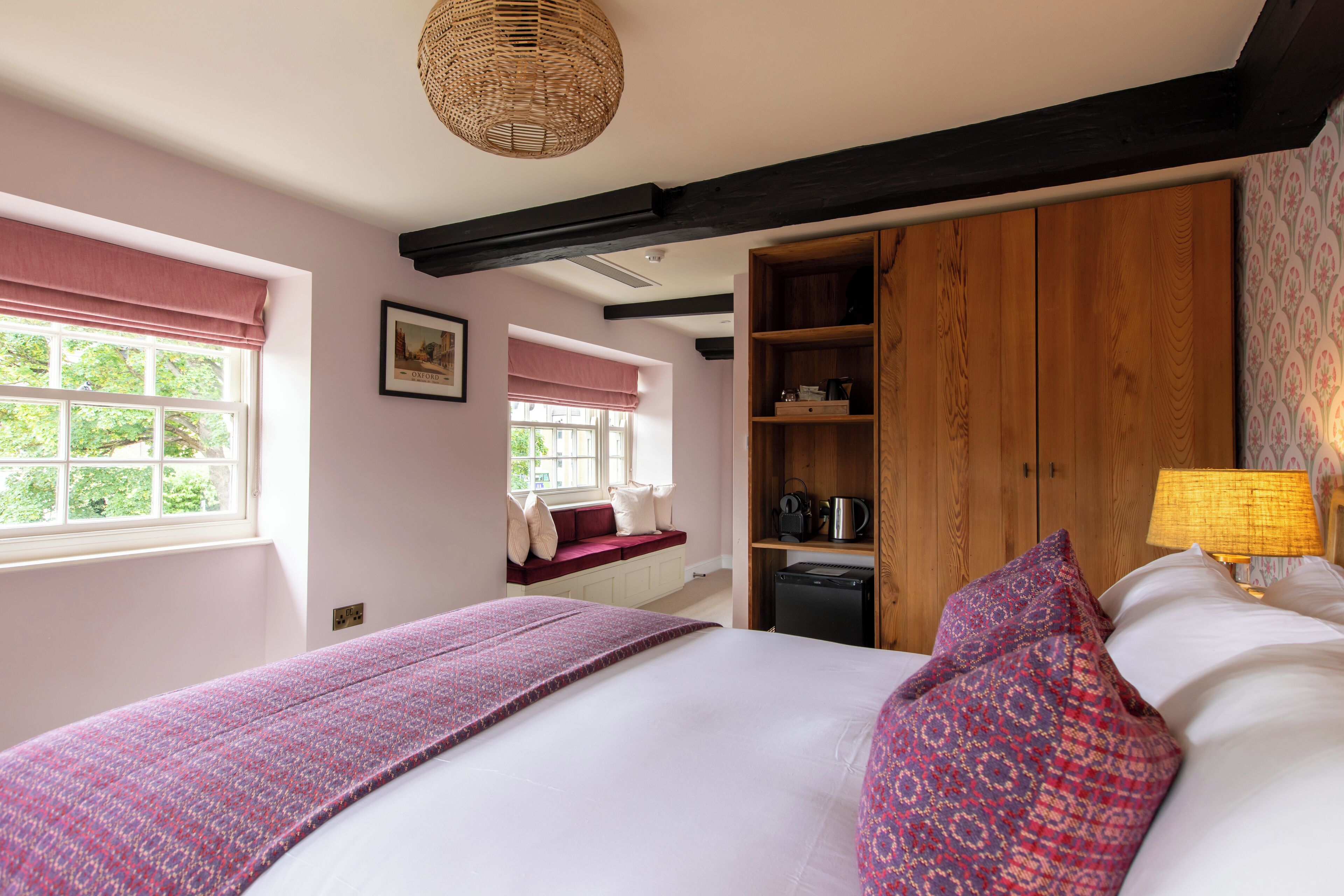 Une chambre à coucher avec un lit, une fenêtre donnant sur un beau paysage, une armoire intégrée et une table de chevet avec une lampe.
