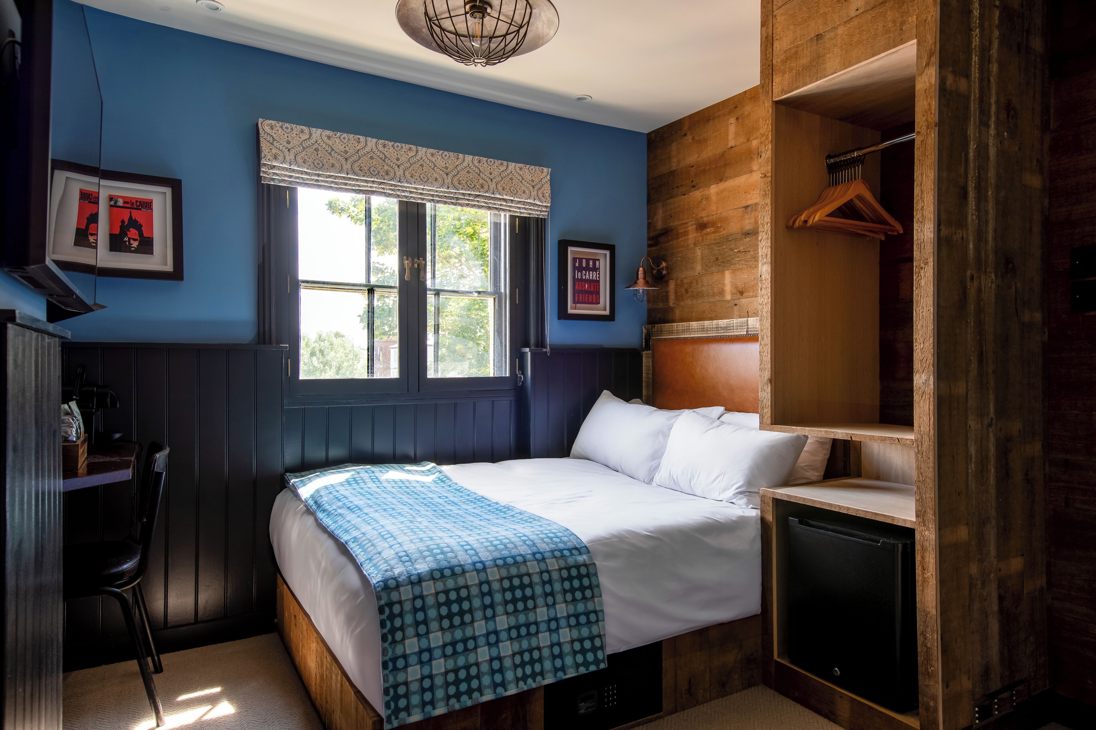 A bedroom with a bed, a desk, a chair, a wardrobe, and a window with curtains.