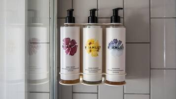Three bottles of Bramble body wash, conditioner, and shampoo on a bathroom shelf.
