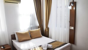 Een hotelkamer met een bed, nachtkastje, airconditioning en een wandlamp.