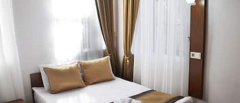 A hotel room with a bed, a nightstand, an air conditioning unit, and a wall-mounted light fixture.