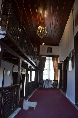Un couloir avec un plafond en bois, un lustre et une moquette rouge.