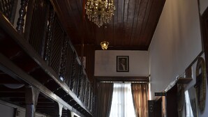 Een statige hal met een houten plafond, een kroonluchter en een rood tapijt.