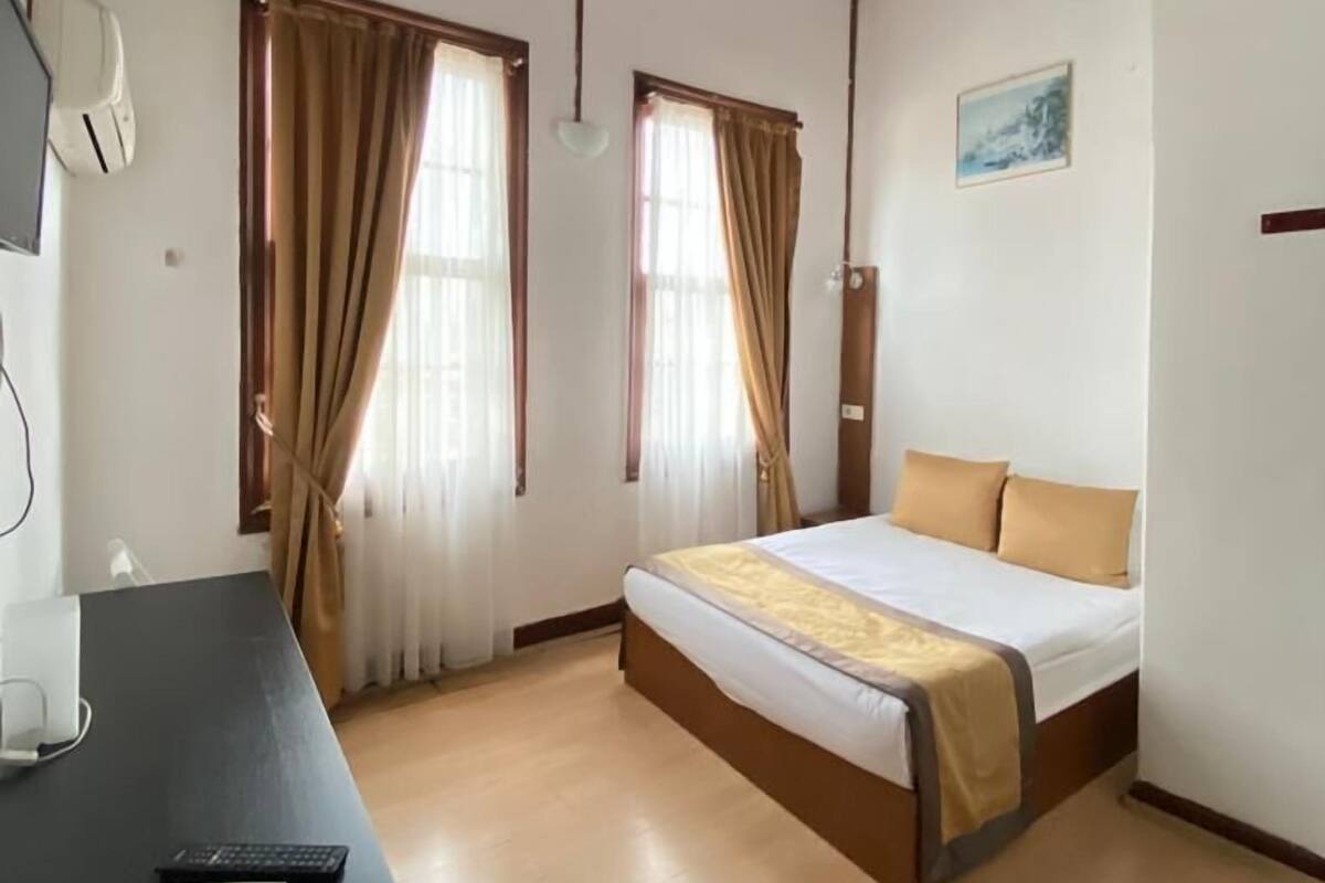 A room with a bed, a desk, and a window with curtains.