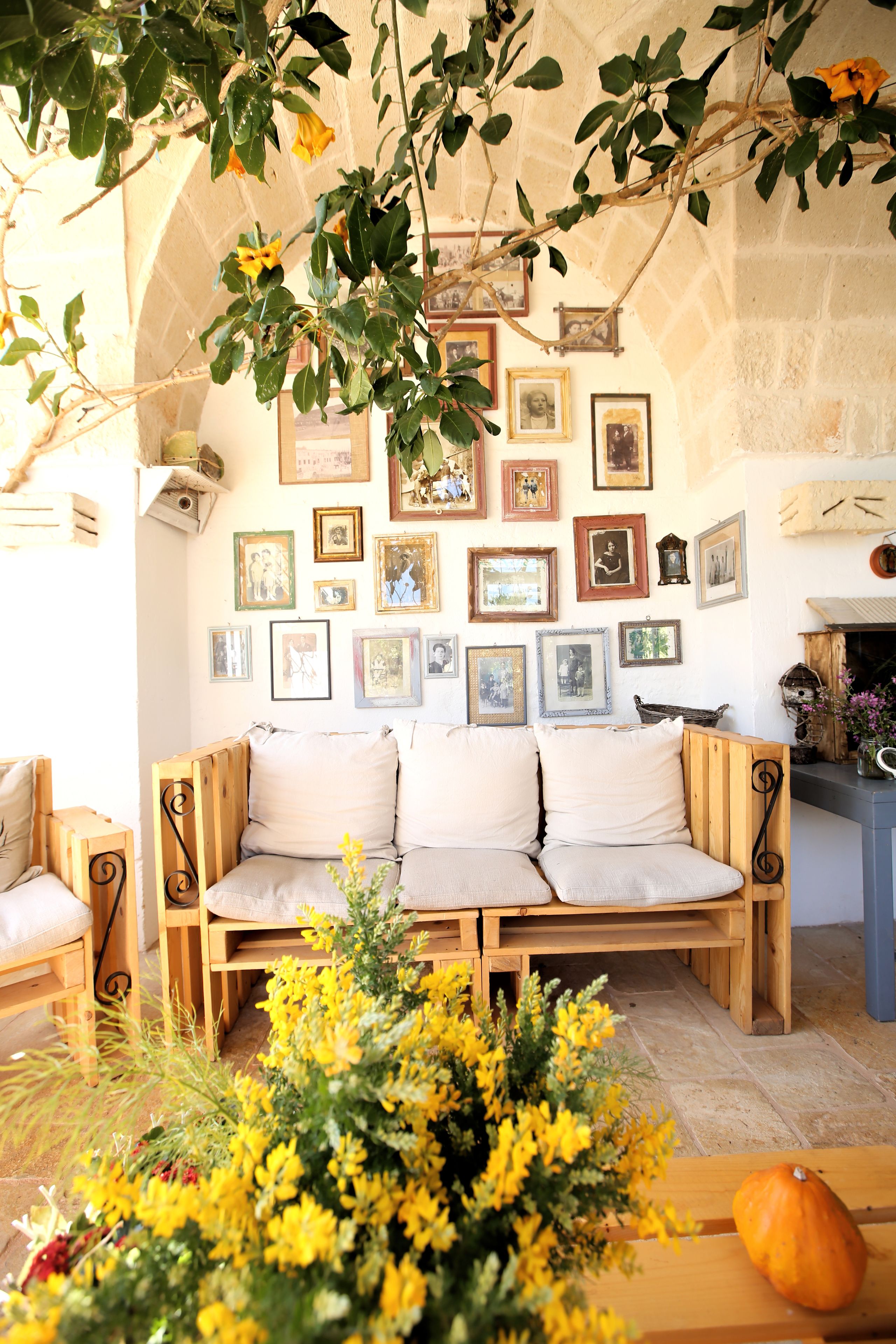 A cozy room with a wooden bench, a vase of yellow flowers, and a wall adorned with framed pictures.
