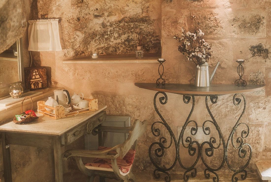 A rustic kitchen with a wooden table, a metal stand, and a vase with dried flowers.