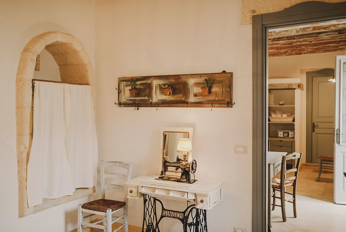 A room with a vintage sewing machine, a mirror, and a wall-mounted plant shelf.