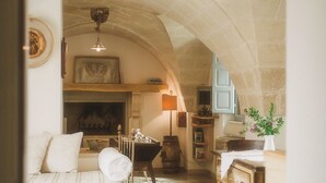 A cozy room with a fireplace, wooden furniture, and stone arches.