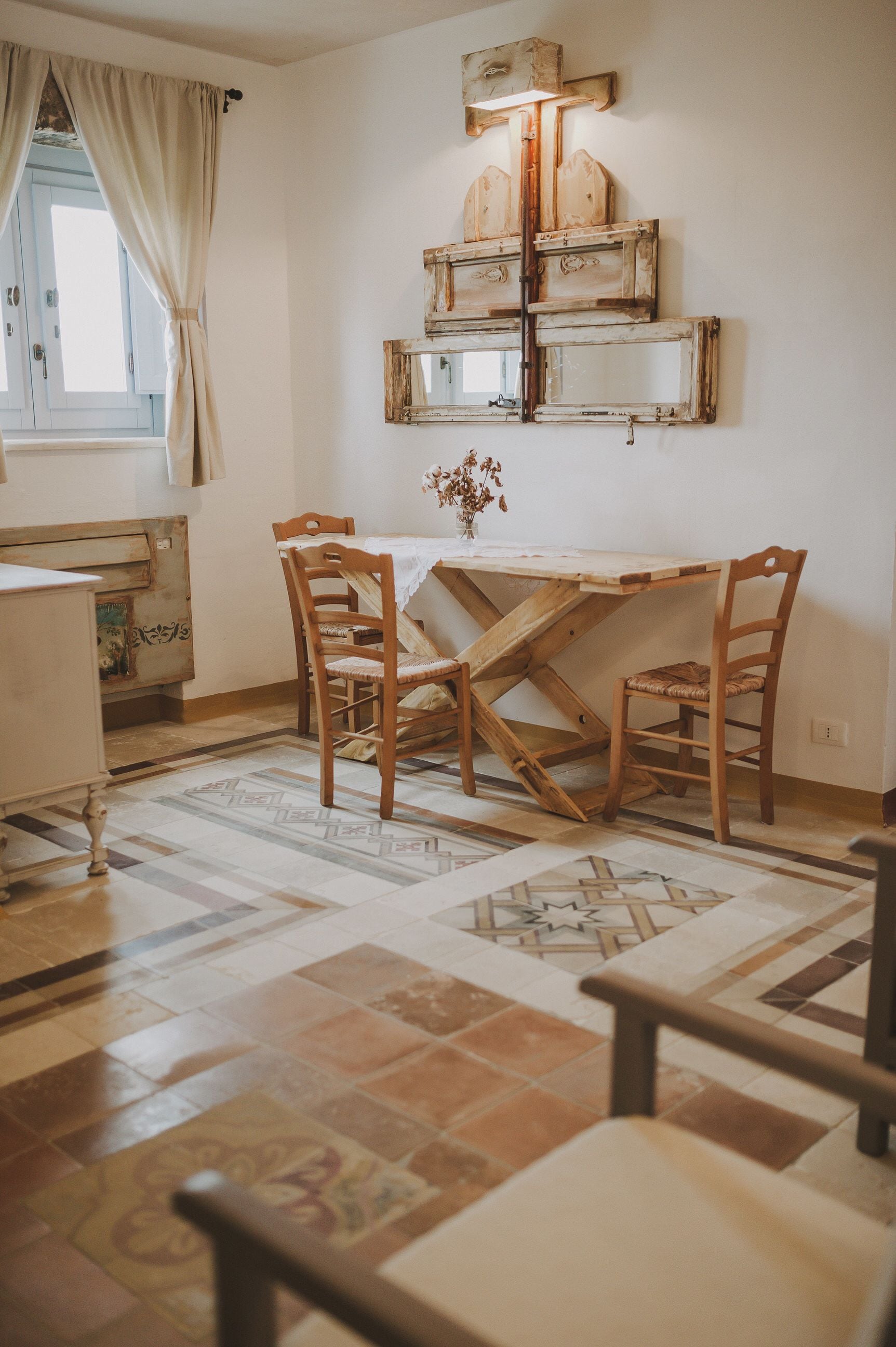 Uma área de refeições com uma mesa e cadeiras de madeira, um espelho decorativo e um piso estampado.