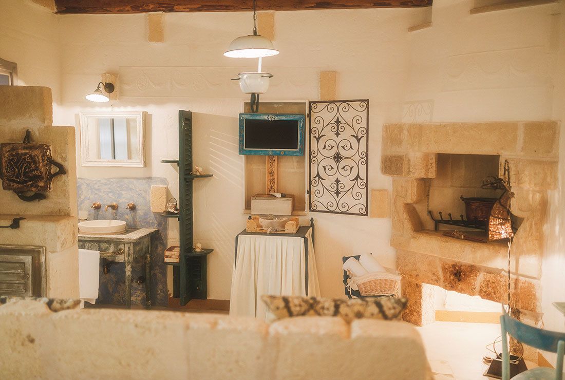 A rustic bathroom with a stone sink, a mirror, a decorative wall piece, and a fireplace.