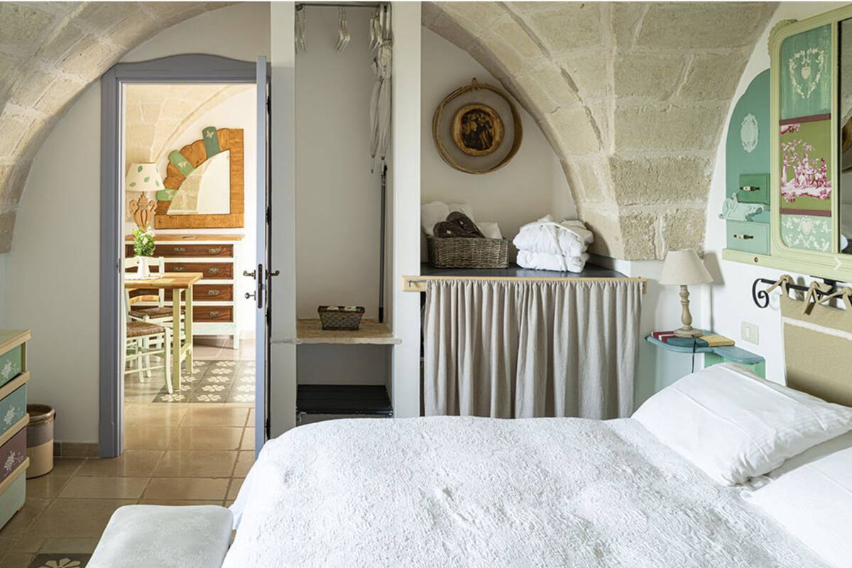 Ein Schlafzimmer mit einem Bett, einem Schminktisch, einem Frisiertisch und einer Tür zu einem Essbereich.