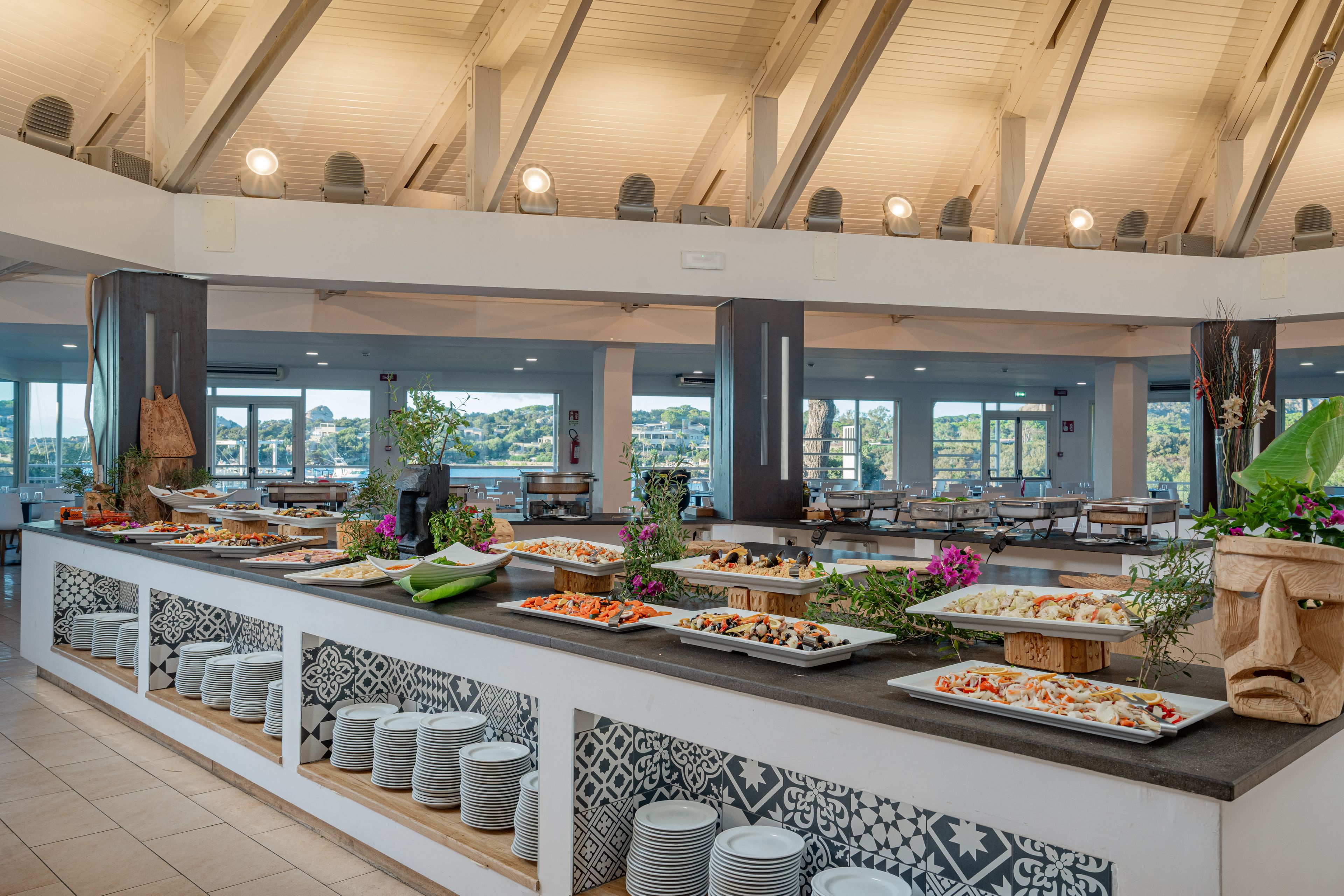 Een buffetgedeelte met meerdere stations, diverse gerechten en uitzicht op het buitenleven door grote ramen.
