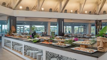 Een buffetgedeelte met meerdere stations, diverse gerechten en uitzicht op het buitenleven door grote ramen.