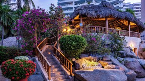 A hotel entrance with a thatched-roof structure, a staircase, and large rocks. - Hotel Irotama Lago (Santa Marta)