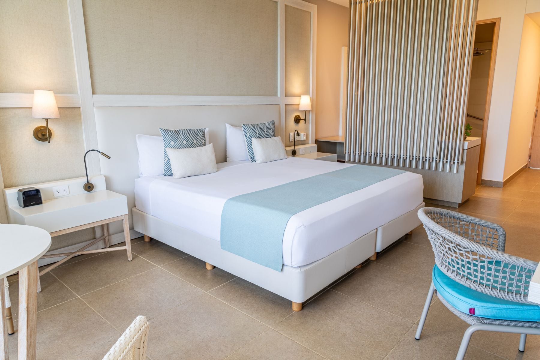 A hotel room with a large bed, bedside tables, a chair, and a curtain divider.