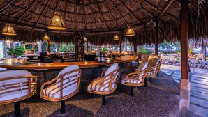 A bar area with a thatched roof, wicker chairs, and hanging lights. - Hotel Irotama Lago (Santa Marta)