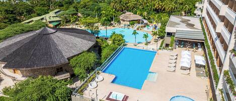 A resort with a large pool, a separate hot tub, and a beach area.
