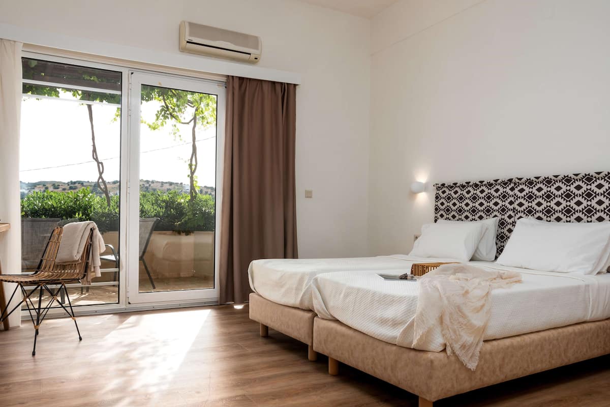 A hotel room with a bed, a chair, and a sliding glass door leading to an outdoor area.