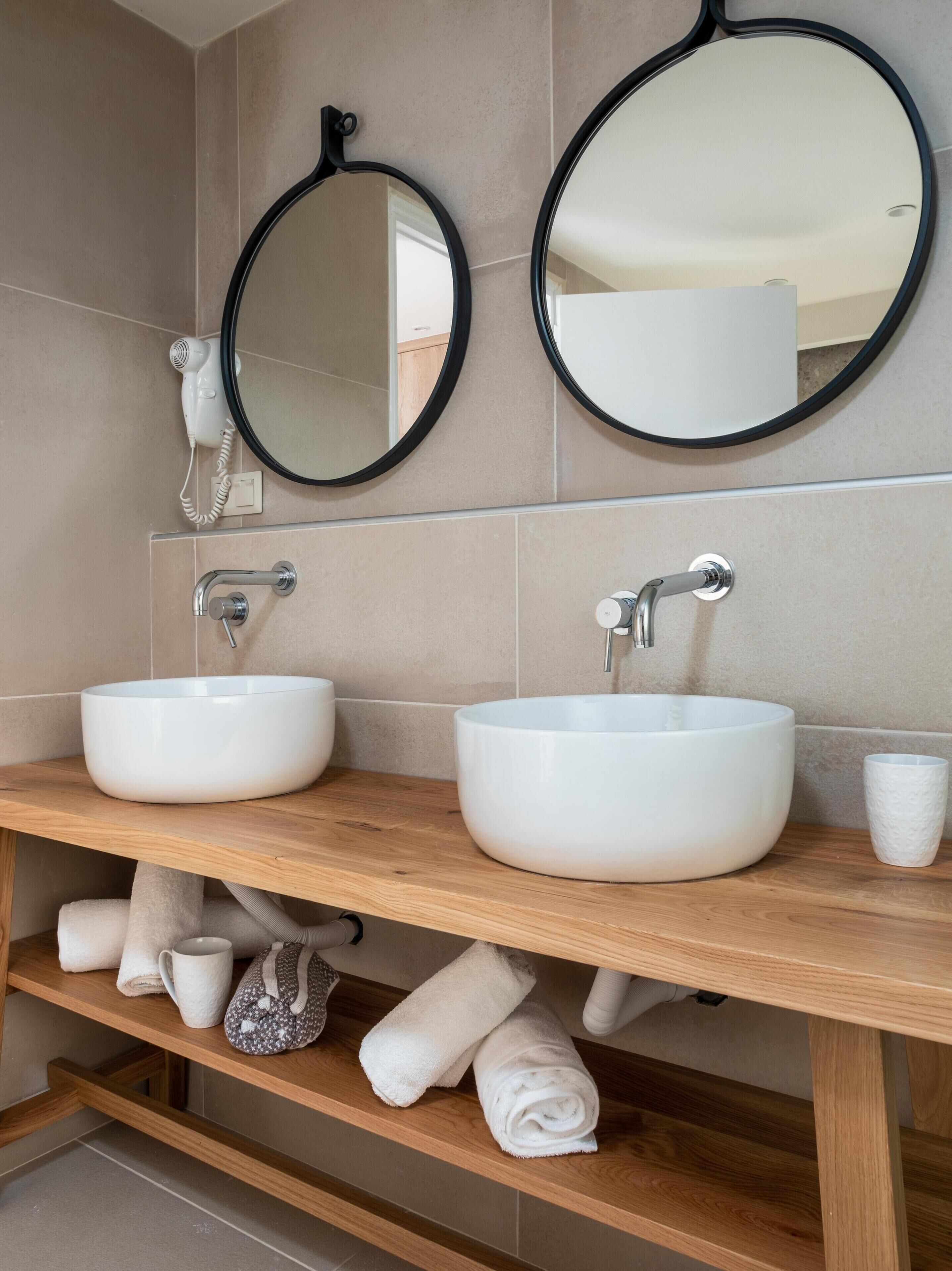 A bathroom with two white sinks, a mirror, and a towel rack.