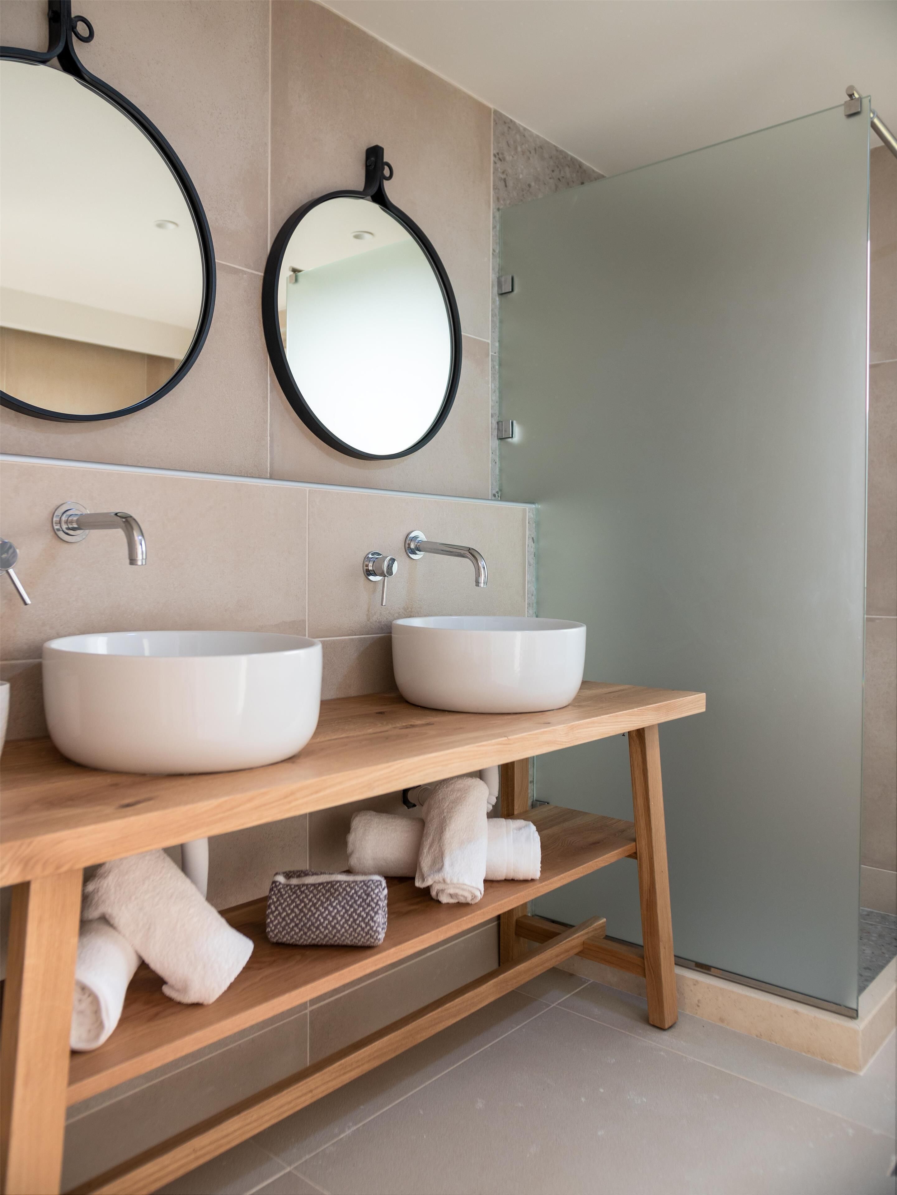 A modern bathroom with two white sinks, a wooden vanity, and a glass shower enclosure.