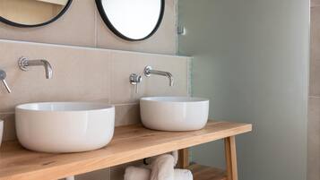 A modern bathroom with two white sinks, a wooden vanity, and a glass shower enclosure.
