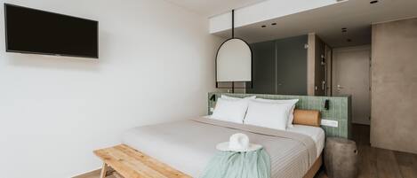 Un dormitorio moderno con cama, una banca, televisor y armario.