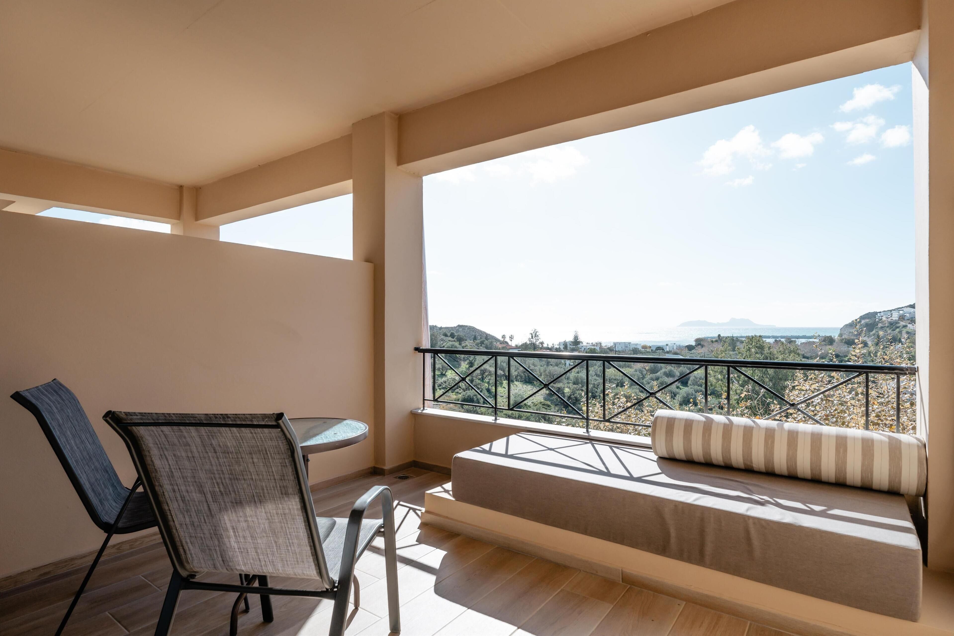 A balcony with a sofa and chairs, overlooking a scenic landscape.