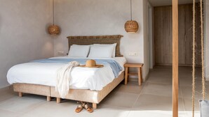 Un dormitorio moderno con una cama grande, una mesita de noche, una lámpara colgante y vistas a una puerta de madera.