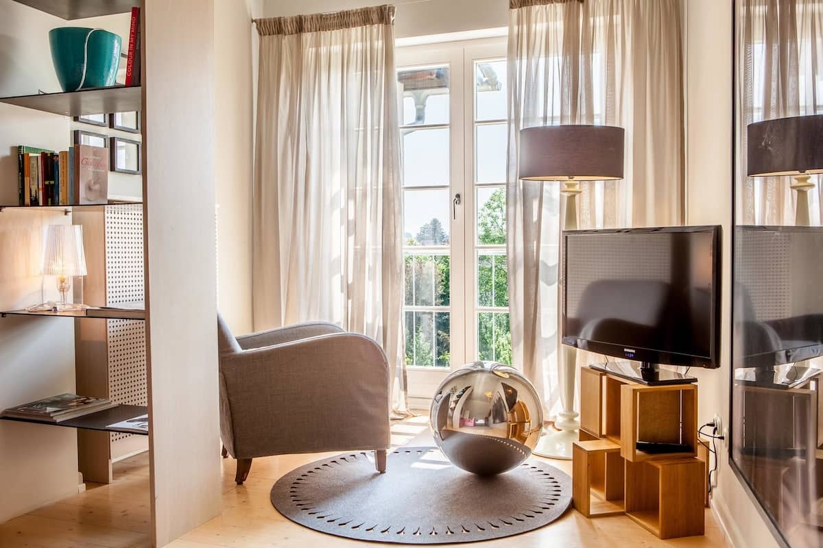 A living room with a sofa, a round rug, a television, and a bookshelf.