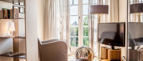 Ein Wohnzimmer mit einer Couch, einem runden Teppich, einem Fernseher und einem Bücherregal.