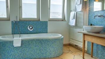 Ein Badezimmer mit freistehender Badewanne, Waschbecken und Fenster.