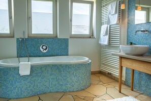 Une salle de bain avec une baignoire sur pieds, un lavabo et une fenêtre.