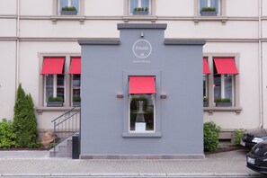Un bâtiment à la façade grise, doté d’auvents rouges et d’une enseigne sur laquelle on peut lire : « Freude Badisches Wittshaus ».
