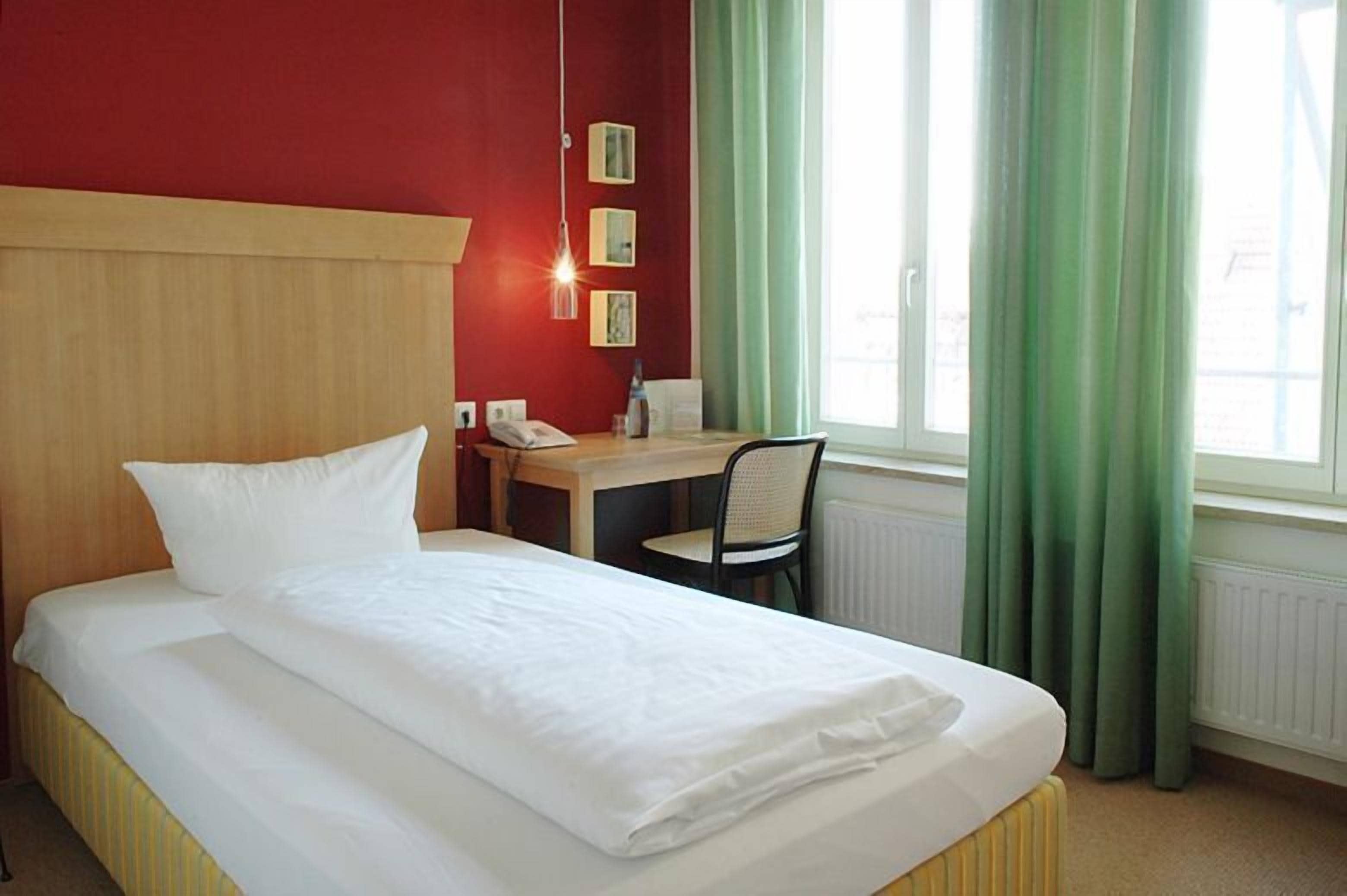 A hotel room with a bed, a desk, and a chair.