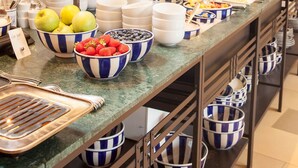 A buffet setup with multiple serving stations, including bowls of fruits, jars of spreads, and a variety of dishes. - DORMERO Hotel Kehl (Kehl)