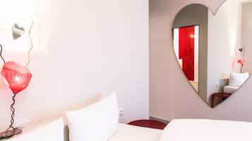 A hotel room with a bed, a heart-shaped mirror, and a red balloon.
