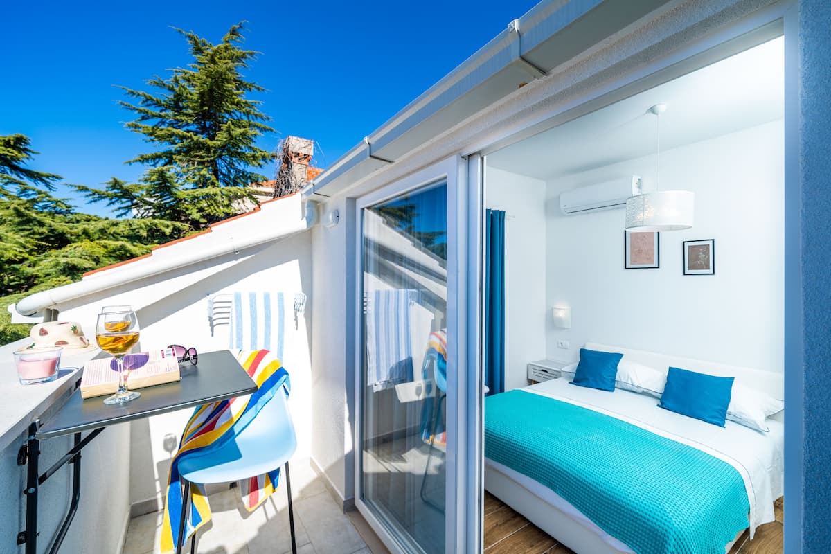 A balcony with a table, chairs, and a bed with blue bedding.