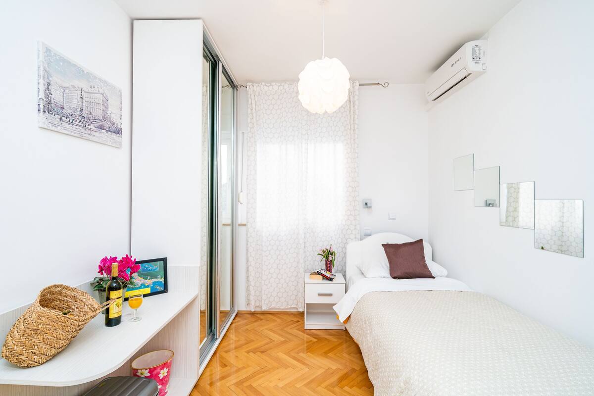 A modern bedroom with a bed, bedside table, and a large window.