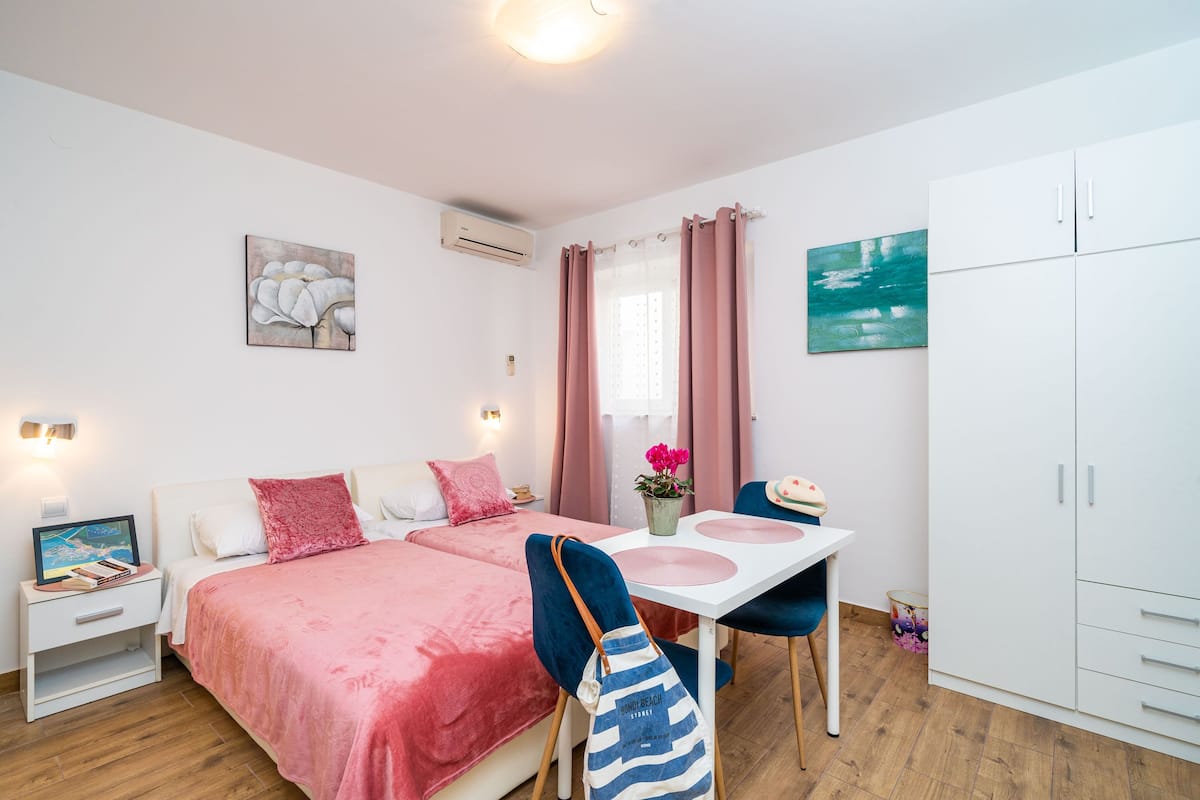A bedroom with a bed, bedside table, chair, wardrobe, and a window with curtains.