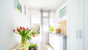 A narrow kitchen with a window, a vase with tulips, a coffee cup, and a plate with pastries. - Jele Rooms (Dubrovnik)