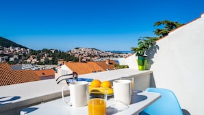 A terrace with breakfast items, a view of a town, and a potted plant. - Jele Rooms (Dubrovnik)