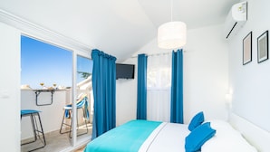 A bedroom with a bed, a TV, and a balcony with blue curtains. - Jele Rooms (Dubrovnik)