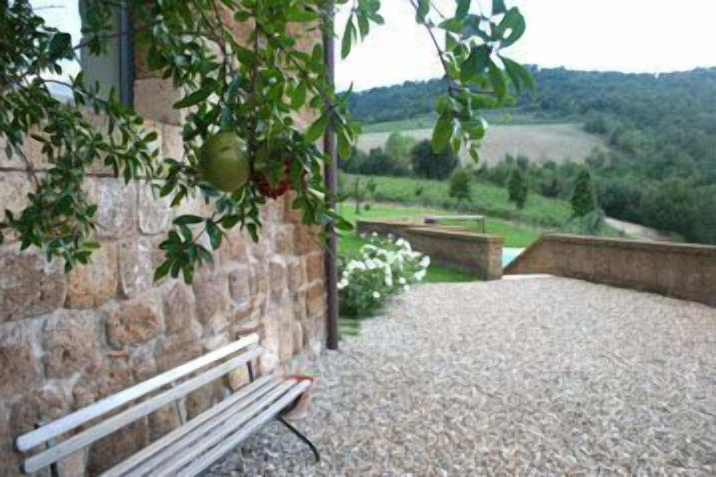 Muro de piedra con un banco y vistas a un paisaje verde.
