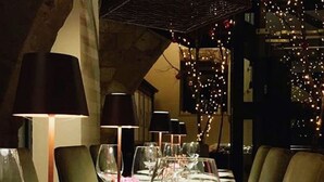 A long dining table set with multiple wine glasses, plates, and cutlery, with chairs on either side.