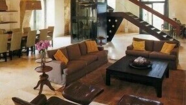 A spacious living area with a high ceiling, a staircase, and a dining area.